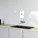 Weißer Durchlauferhitzer von Stiebel Eltron, wandmontiert, mit einem Bedienfeld und einem Auslass, installiert über einer schwarzen Spüle in einer modernen Küche.